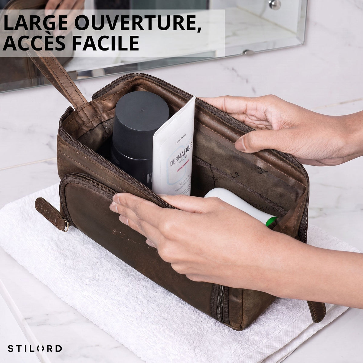 Trousse de toilette Henry en cuir zamora marron, vue ouverte par le dessus, produits visibles à l'intérieur, main tenant la trousse, logo STILORD visible