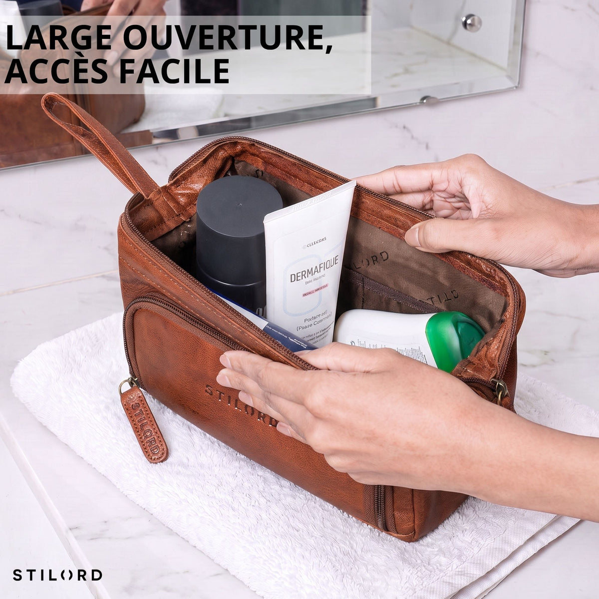 Trousse de toilette en cuir marron (maraska), large ouverture en vue intérieure, mains tenant la trousse et produits visibles, embossage STILORD